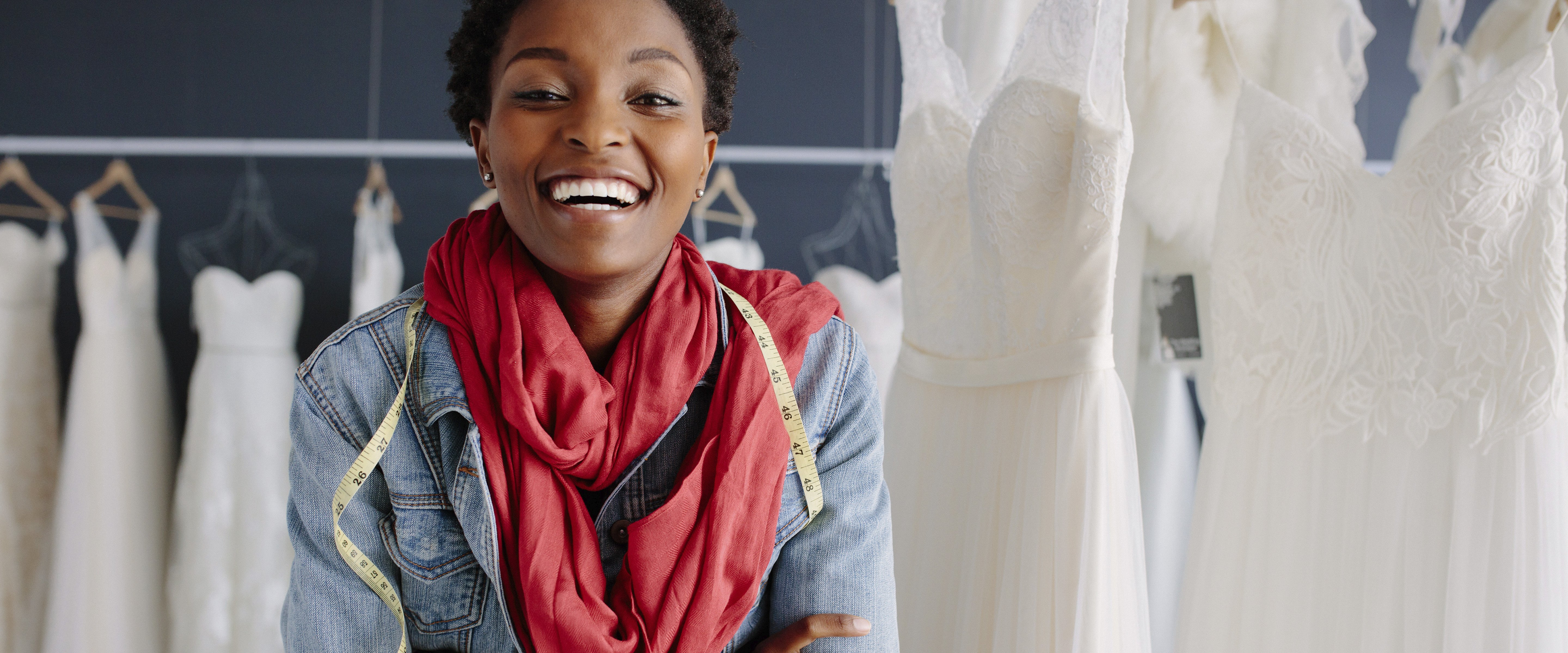 smiling bridal boutique owner next to racks of white dresses
