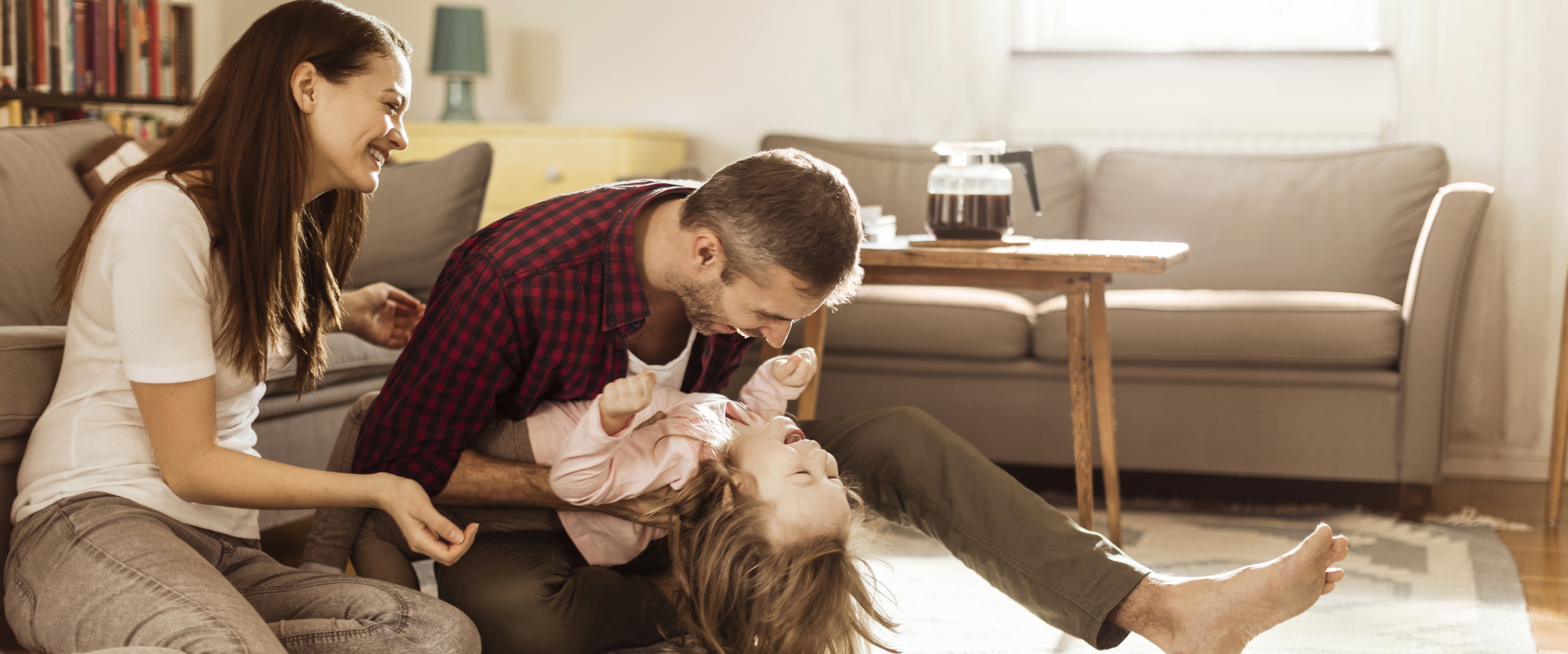 parents playing with their daughter in modern living room
