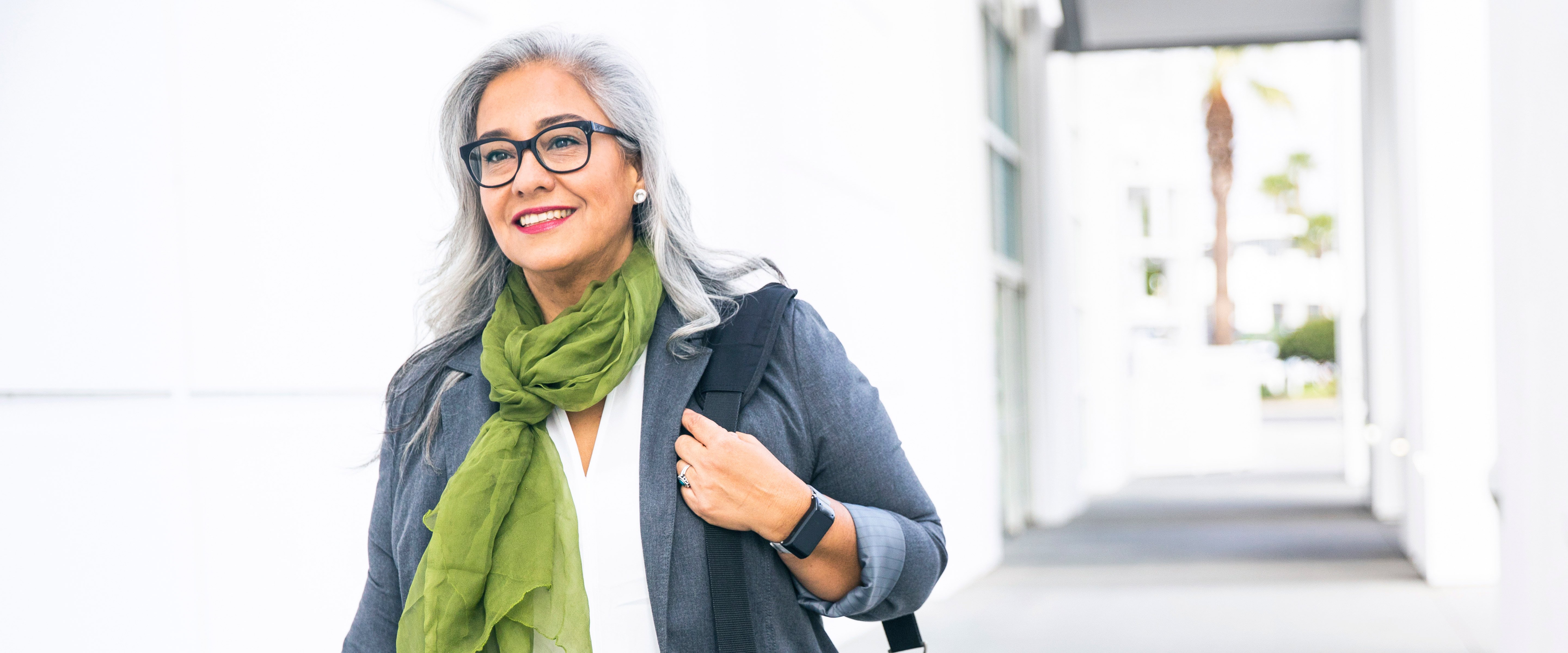 older woman going out wearing scarf, backpack, and smart watch