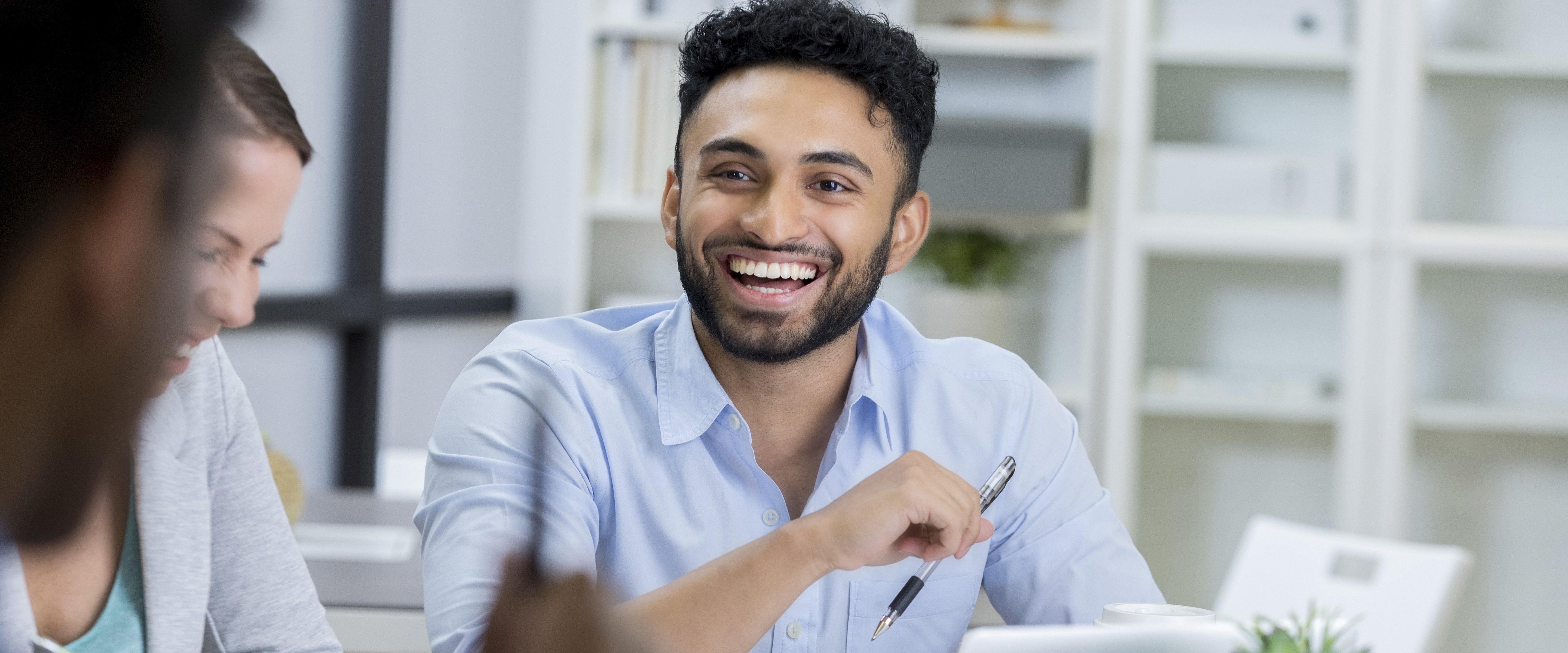 smiling man with pen discussing project with coworkers